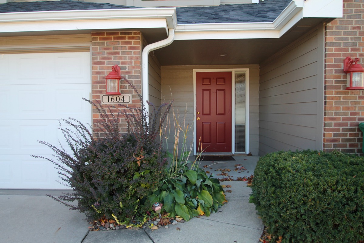 Private townhome entrance with brick facade and red front door